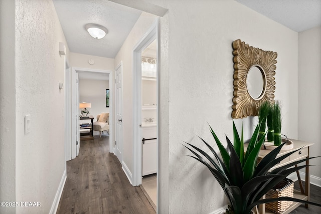 hallway with a sink, baseboards, and wood finished floors