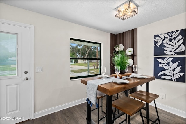 dining area featuring dark wood finished floors, baseboards, and a textured ceiling