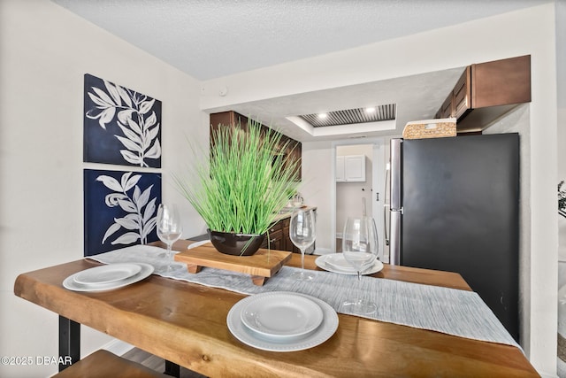 dining area with a raised ceiling and a textured ceiling