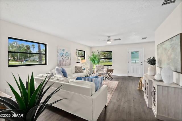 living area with visible vents, dark wood-type flooring, ceiling fan, and a textured ceiling