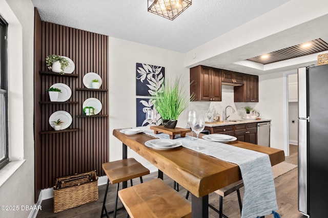 dining area with a textured ceiling, baseboards, and wood finished floors