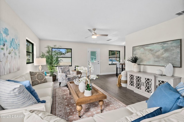 living room featuring visible vents, baseboards, ceiling fan, and wood finished floors