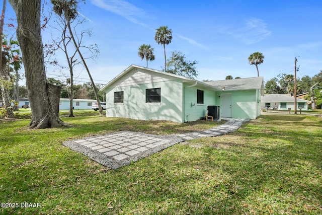 rear view of property with central AC and a lawn