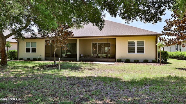 back of property featuring a sunroom, stucco siding, and a yard