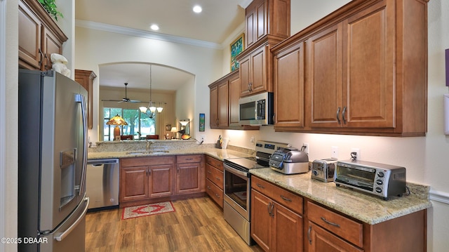 kitchen featuring brown cabinetry, appliances with stainless steel finishes, wood finished floors, a sink, and a toaster