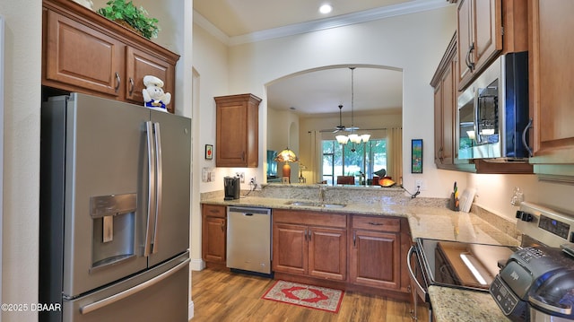 kitchen featuring appliances with stainless steel finishes, arched walkways, a sink, light stone counters, and light wood-style flooring