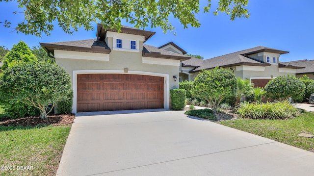 view of front of house featuring a garage, roof with shingles, stucco siding, and concrete driveway