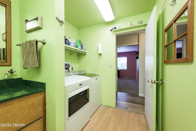 clothes washing area with washing machine and dryer, laundry area, and light wood-style flooring