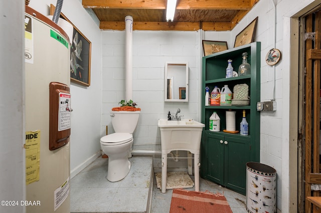 bathroom featuring concrete block wall, electric water heater, vanity, and toilet