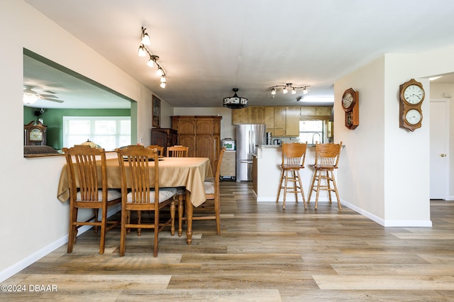 dining space with light wood-type flooring, baseboards, and track lighting