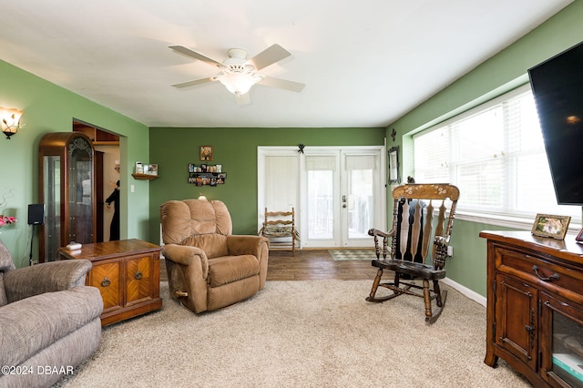 living area with light carpet, ceiling fan, and baseboards