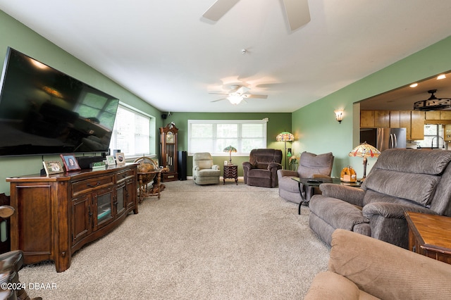 living area with light carpet and ceiling fan