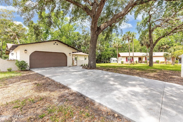 886 Lindenwood Cir W, Ormond Beach, FL 32174 - view of front of house featuring concrete driveway, an attached garage, stucco siding, a front yard, and view of scattered trees