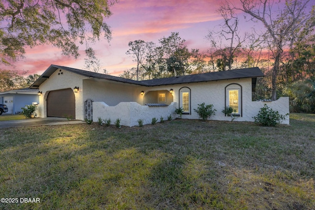 ranch-style home with a garage and a lawn