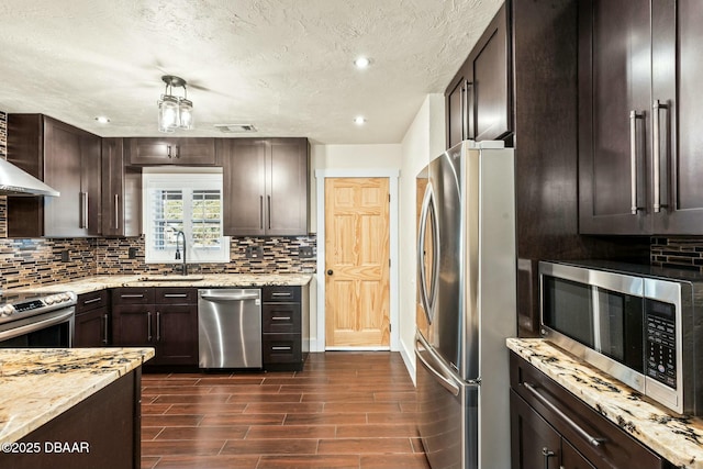 kitchen with dark brown cabinetry, sink, light stone counters, tasteful backsplash, and stainless steel appliances