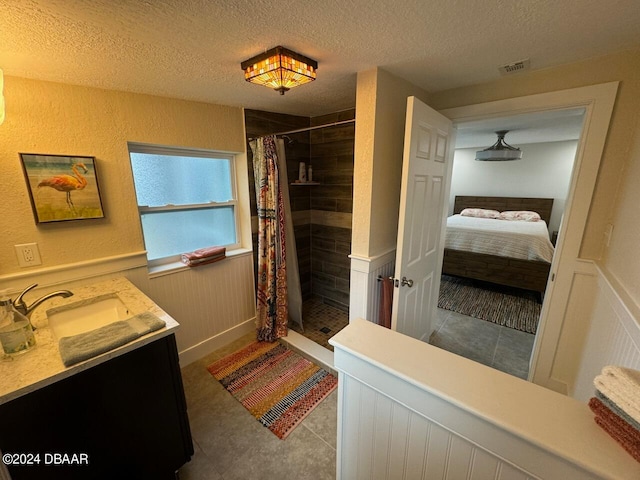 bathroom with a shower with shower curtain, vanity, and a textured ceiling