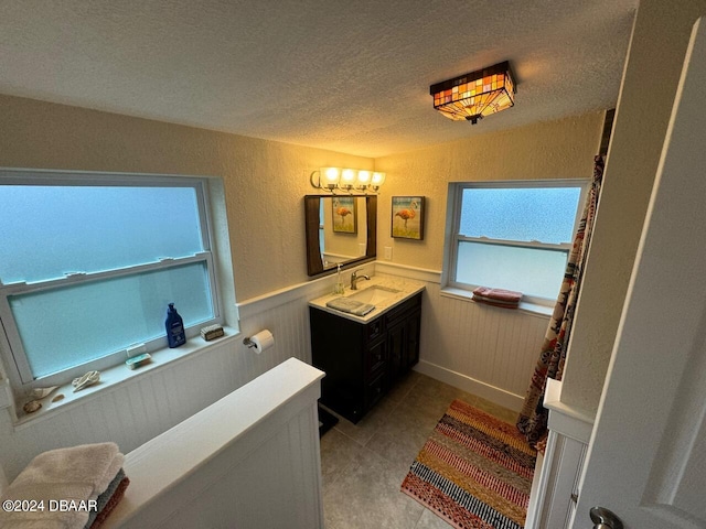 bathroom with tile patterned flooring, vanity, a textured ceiling, and an inviting chandelier