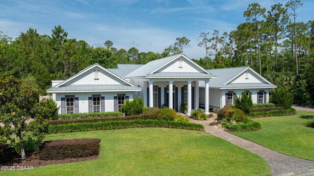 3 Ashford Lakes Dr, Ormond Beach, FL 32174 - greek revival house with a front lawn, a standing seam roof, metal roof, and stucco siding