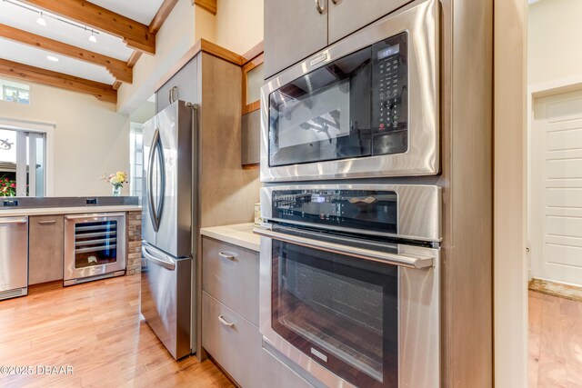 3 Ashford Lakes Dr, Ormond Beach, FL 32174 - kitchen featuring appliances with stainless steel finishes, wine cooler, beamed ceiling, light wood-style floors, and light countertops