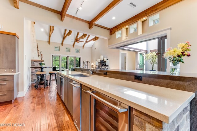 3 Ashford Lakes Dr, Ormond Beach, FL 32174 - kitchen featuring beverage cooler, beamed ceiling, light wood-style floors, a sink, and light countertops
