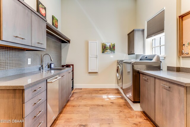 3 Ashford Lakes Dr, Ormond Beach, FL 32174 - kitchen with a sink, dishwasher, washing machine and dryer, light wood-style floors, and backsplash