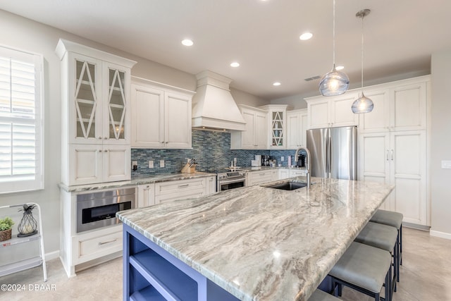 kitchen featuring stainless steel appliances, premium range hood, sink, and a large island