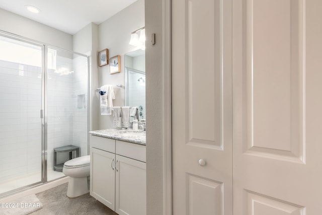 bathroom featuring a shower with door, vanity, toilet, and tile patterned floors