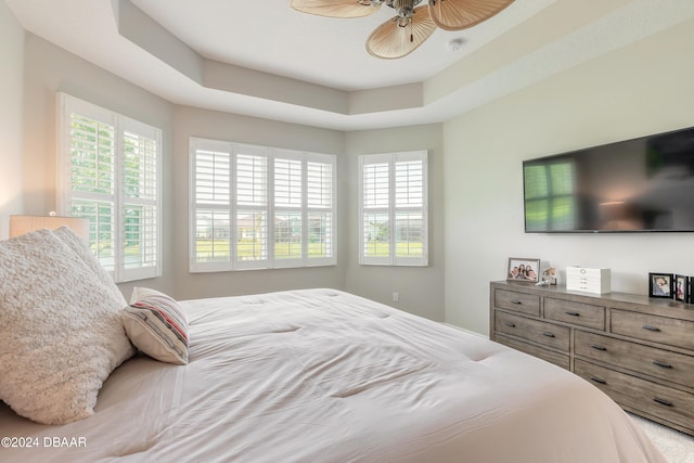 bedroom with ceiling fan and a tray ceiling