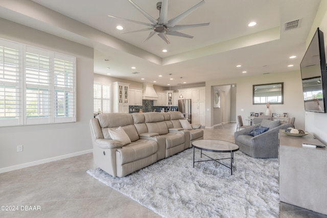 living room featuring ceiling fan and a raised ceiling