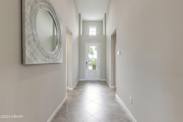 doorway featuring light tile patterned flooring and a towering ceiling