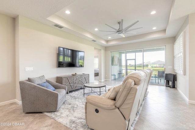 living room with ceiling fan and a tray ceiling