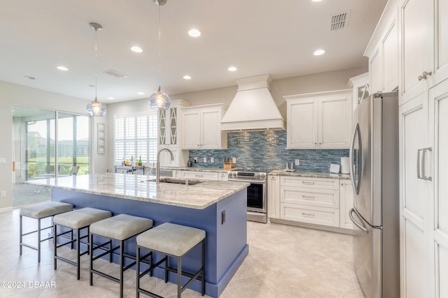 kitchen with stainless steel appliances, sink, custom exhaust hood, an island with sink, and white cabinetry