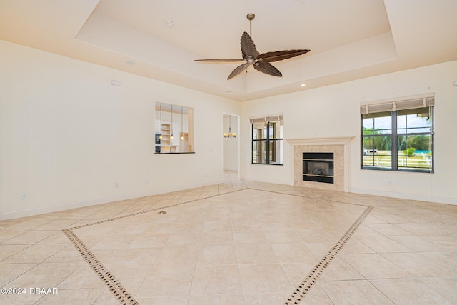 unfurnished living room with baseboards, a raised ceiling, and tile patterned flooring