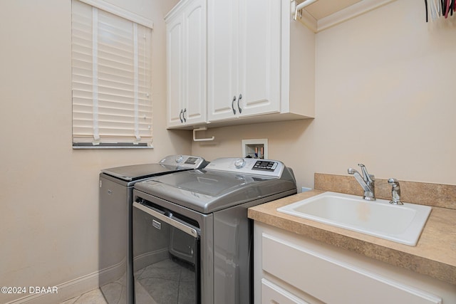 laundry area featuring a sink, baseboards, cabinet space, and washing machine and clothes dryer