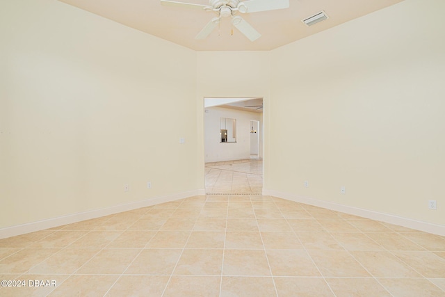 spare room featuring light tile patterned floors, a ceiling fan, visible vents, and baseboards