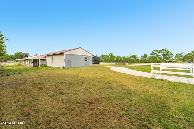 view of yard featuring an outbuilding, a rural view, and fence