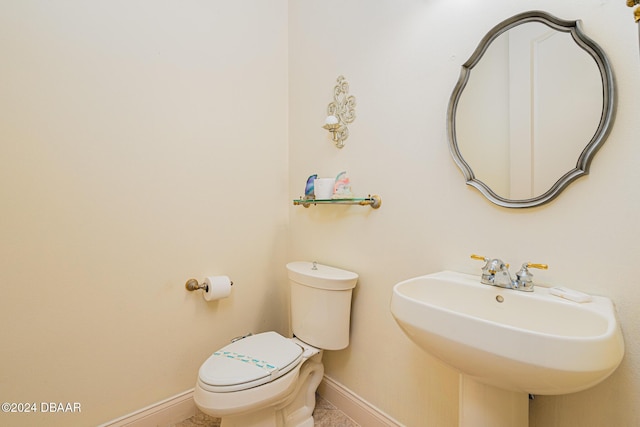 bathroom featuring toilet, baseboards, and a sink