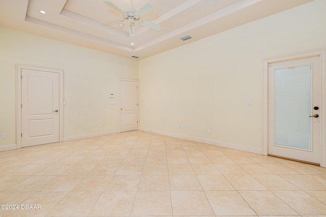 empty room featuring visible vents, a raised ceiling, and baseboards