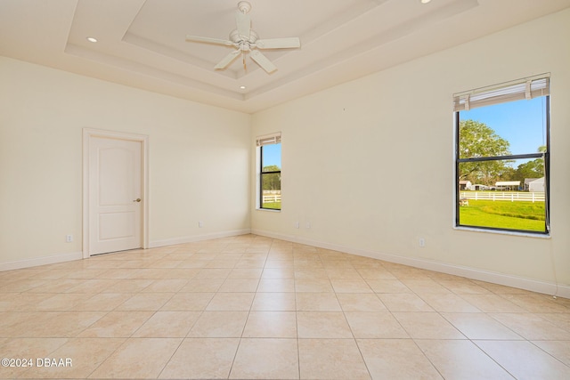 empty room featuring a wealth of natural light, a raised ceiling, and baseboards