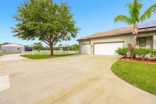 view of side of home with driveway, stucco siding, a garage, a lawn, and roof mounted solar panels