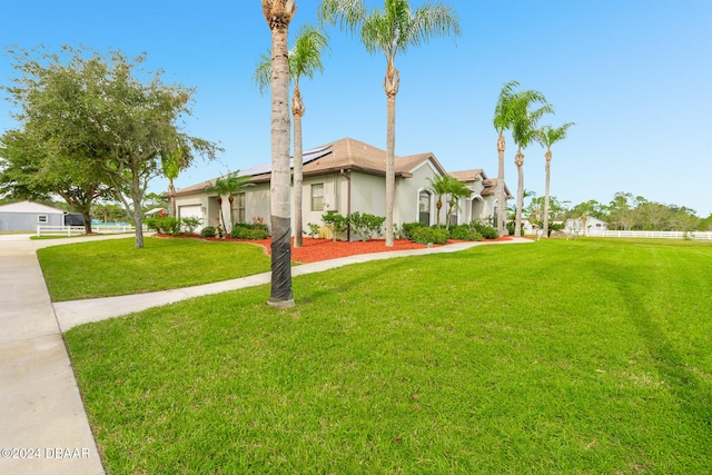 view of front facade featuring solar panels, concrete driveway, a front yard, stucco siding, and a garage