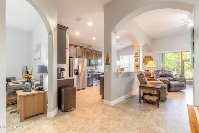 kitchen featuring kitchen peninsula, appliances with stainless steel finishes, ceiling fan, a breakfast bar area, and lofted ceiling