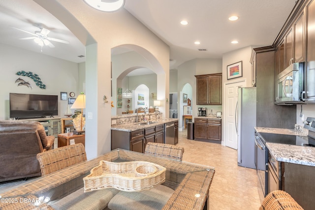 kitchen with dark brown cabinetry, light stone counters, sink, and stainless steel appliances