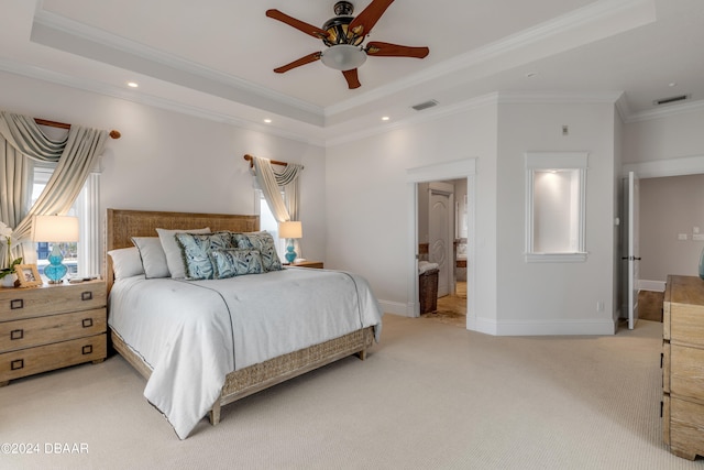 bedroom featuring ornamental molding, connected bathroom, light carpet, a tray ceiling, and ceiling fan