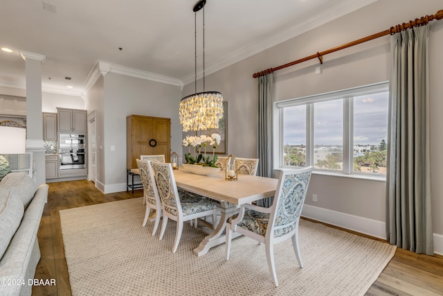 dining room featuring light hardwood / wood-style floors, crown molding, and a notable chandelier