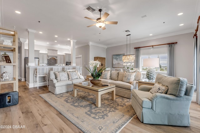 living room with ornamental molding, ceiling fan with notable chandelier, light hardwood / wood-style floors, and ornate columns