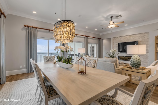 dining room featuring ornamental molding, light wood-type flooring, and ceiling fan with notable chandelier