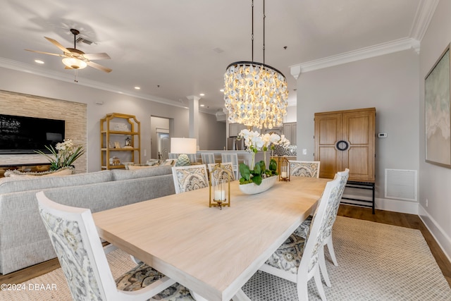 dining space with decorative columns, ceiling fan with notable chandelier, light wood-type flooring, and ornamental molding