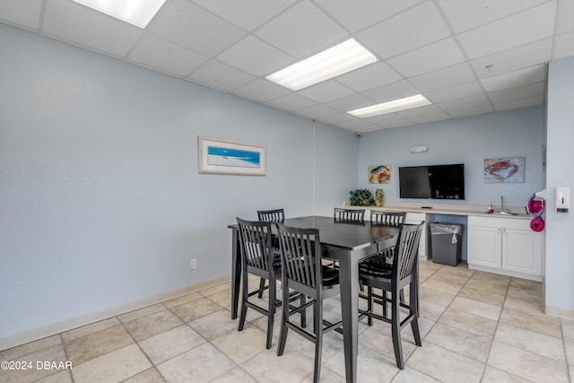 dining space with a drop ceiling, sink, and light tile patterned flooring