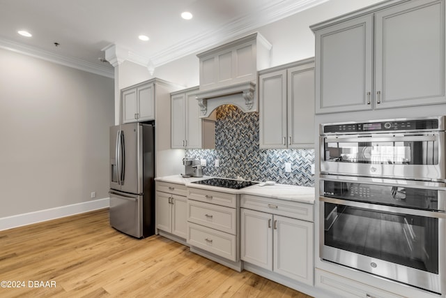 kitchen featuring stainless steel appliances, light hardwood / wood-style floors, tasteful backsplash, ornamental molding, and gray cabinets